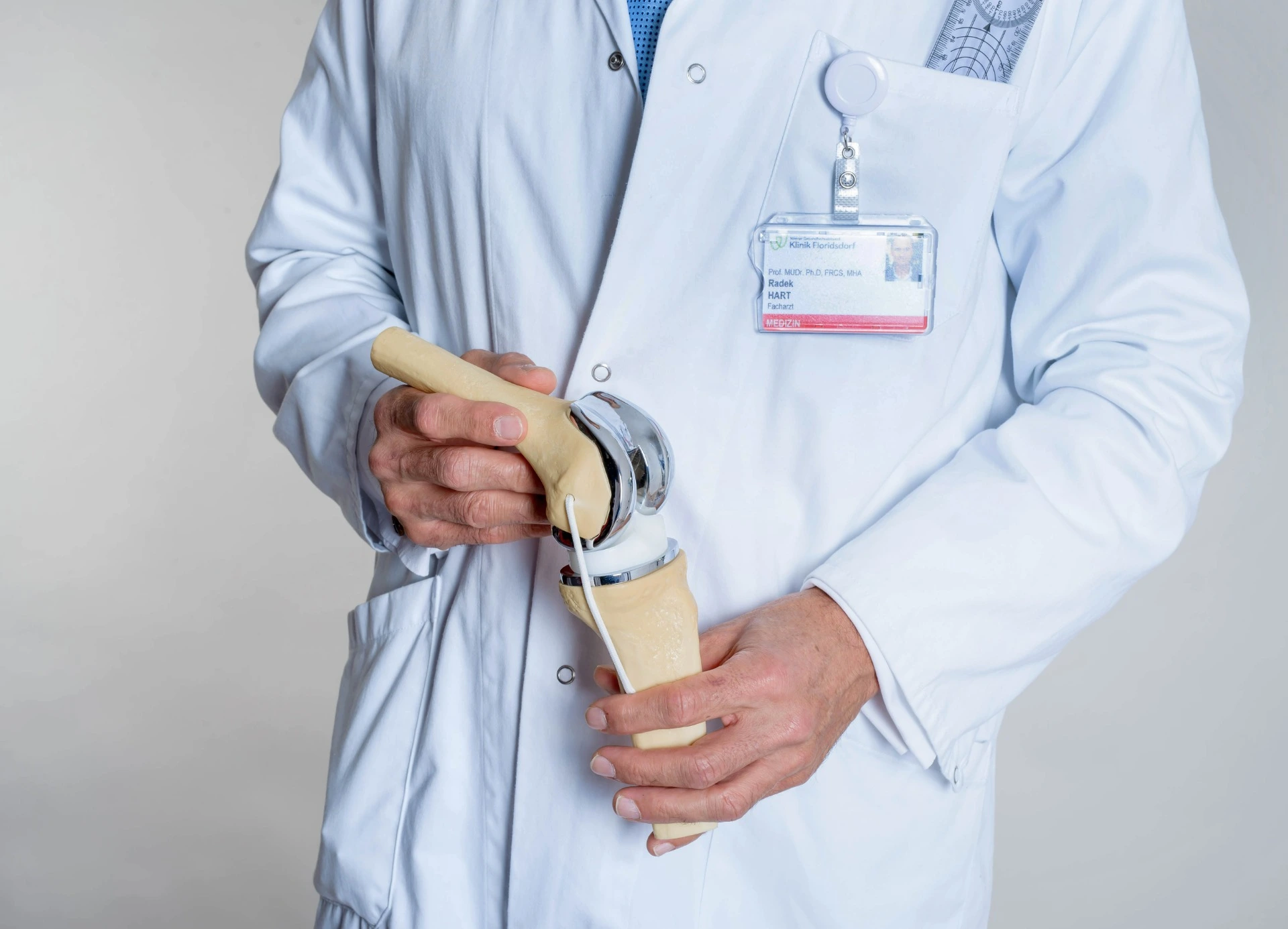 Ein Arzt hält ein künstliches Kniegelenk in der Hand.